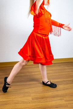 charming 5-year-old blonde girl, dancer in vibrant red dress performs Latin dance steps, showing energy, elegance, and early dedication to art
