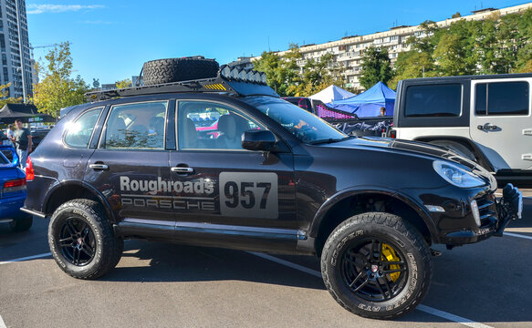 Custom black Porsche Cayenne SUV rally build features a lifted suspension, all-terrain tires, bumper Hella lights, and a roof LED light rack