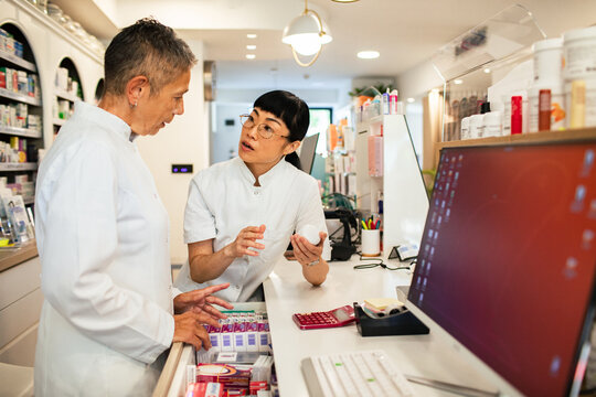 Pharmacists discussing medication at pharmacy counter