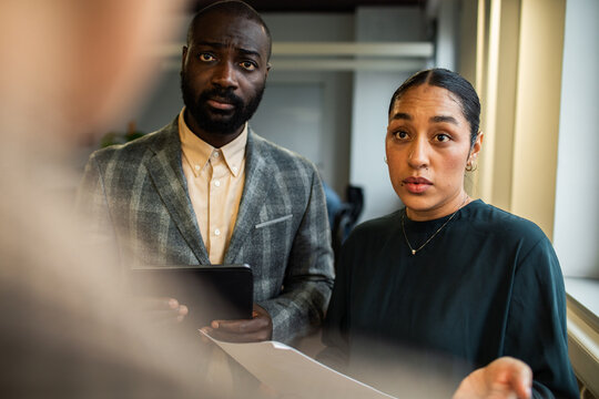 Two concerned coworkers discussing report by office window