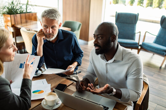 Diverse colleagues discussing financial reports in cafe
