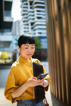 Professional woman using smartphone on modern city street
