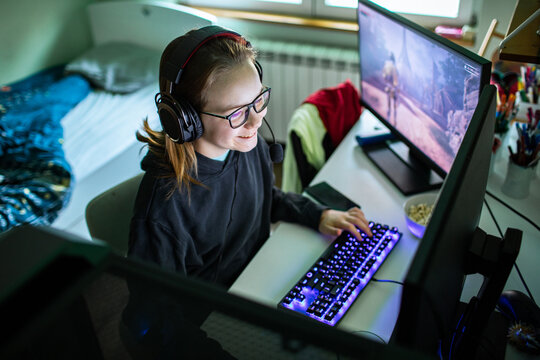 Teen girl gaming on desktop computer in bedroom