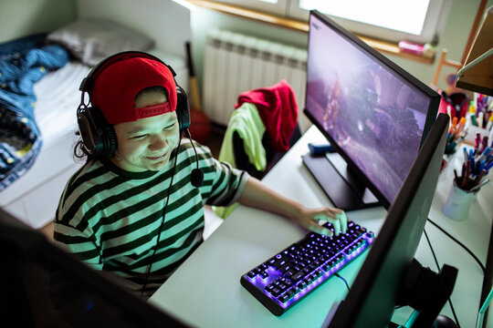 Smiling teen gamer with headset at home desk