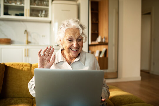 Smiling senior woman video calling on laptop at home