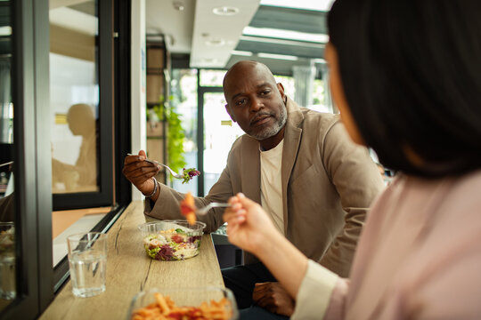 Coworkers eating lunch together at modern cafe counter