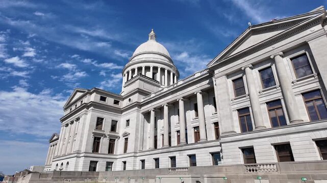 White neoclassical capitol building with dome under blue sky.