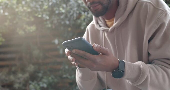 African American man reading phone text, scrolling, laughing in yard with hoodie, watch, copy space