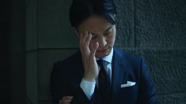 Businessman looking down at his hands in a dimly lit passage