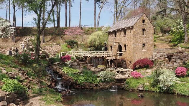 Stone mill with waterwheel and bridge in garden.
