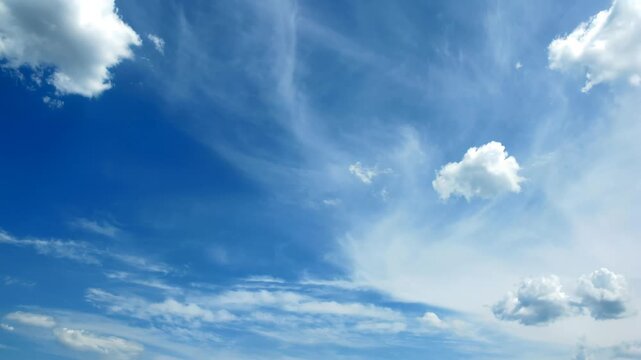 Time-lapse of dynamic white cumulus and cirrus clouds drifting across a vivid blue sky, serene and peaceful natural background
