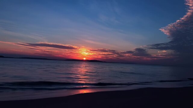 Serene sunset over calm ocean with vibrant red and purple sky, gentle waves lapping sandy shore at twilight