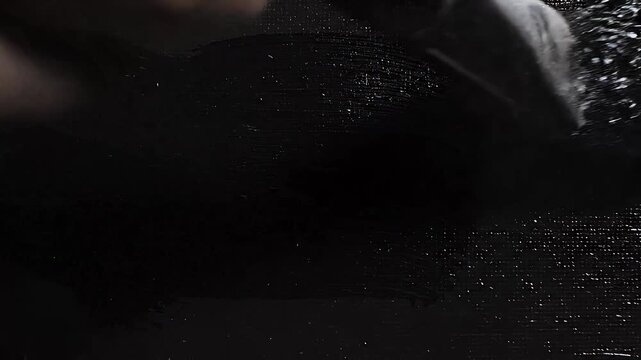 Paintbrush creating thick black acrylic strokes on white canvas in this artistic motion video footage clip