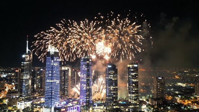 Golden fireworks exploding over an illuminated city skyline at night