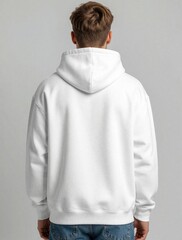 Fototapeta premium Back view of young man wearing blank white hoodie mockup. Male person shows empty sweatshirt for clothing design. Casual streetwear style with cotton textile. Model stands against grey background,