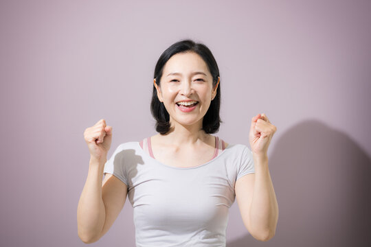 笑顔でピラティスやヨガ、エクササイズをする女性、ガッツポーズで健康維持や運動習慣を楽しむ日本人ミドル女性のフィットネス　カメラ目線の笑顔　更年期のダイエット成功などのイメージ