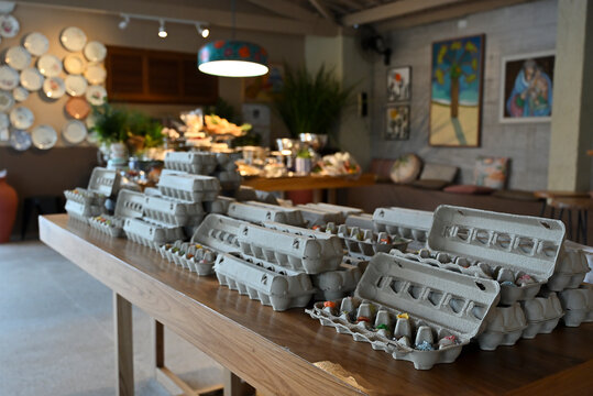 gourmet sweets and brigadeiros arranged in recycled egg cartons on wooden table, creative rustic brazilian event party favors display, wide horizontal shot