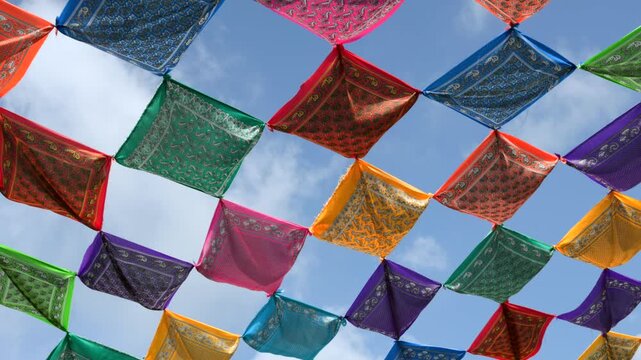 Colorful mexican festival bandanas hanging and waving in the wind against a blue sky