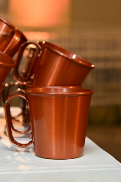 copper moscow mule mugs stacked on buffet table for drink service at luxury brazilian event, bar catering decor, close up vertical shot