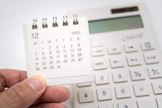 Hand holding December calendar with calculator for financial schedule and payment deadline concept. monthly budget planning, tax season schedule, financial time management, bill due date reminder