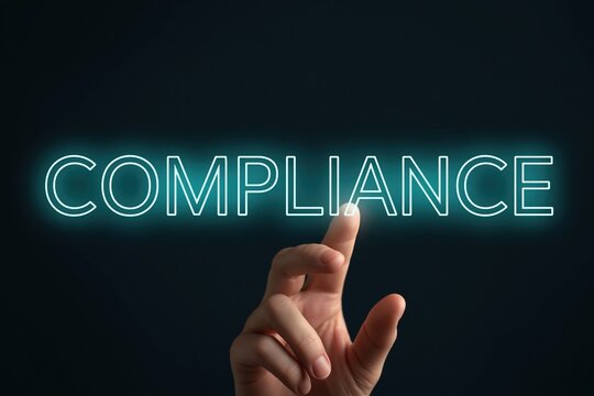 Hand touching glowing compliance text against dark background