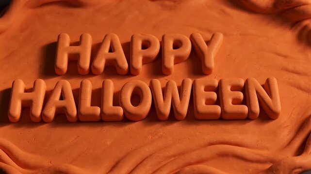 Happy Halloween typography constructed from orange modeling clay letters on a textured background for seasonal celebration