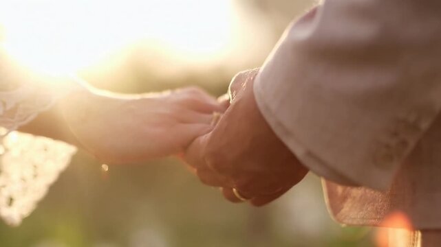 Close-up video of a couple holding hands, captured at a romantic, low-angle view.