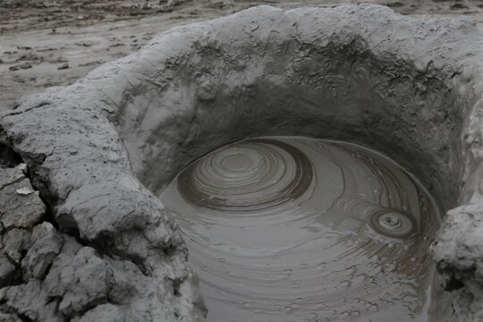 A close-up shot of a bubbling mud volcano crater
