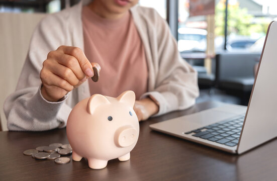 A woman putting her savings into a piggy bank. Symbolizing personal savings, financial planning and smart money management.