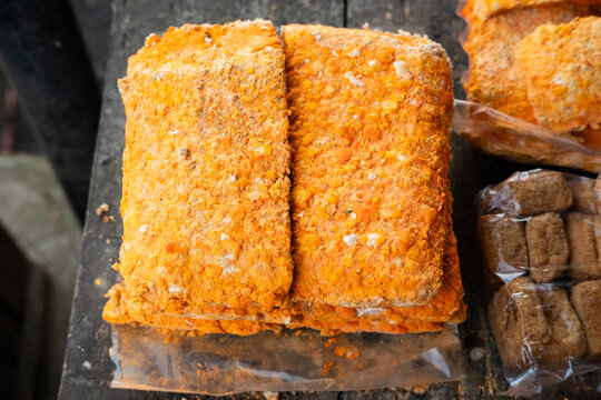Close‑up of orange oncom fermented soybean cake with textured surface. Perfect for Indonesian cuisine, Sundanese food visuals, traditional cooking, and cultural design projects.