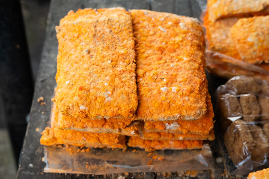 Close‑up of orange oncom fermented soybean cake with textured surface. Perfect for culinary themes, Indonesian food visuals, traditional cuisine, and creative design projects.