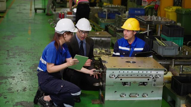 Industrial engineers and factory supervisor discussing technical project details during quality control inspection in manufacturing facility
