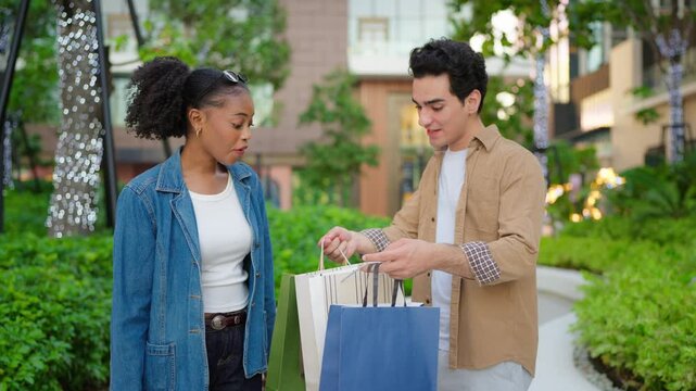 Latino man and Black woman walking outdoors while shopping in the city. 