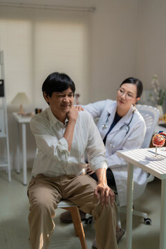 Asian Female Doctor Examining Senior Patient Suffering from Severe Lower Back Pain