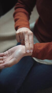 Anonymous woman checking her pulse with her hand, illustrating heart rate monitoring, health awareness, and personal wellness in a close-up video.
