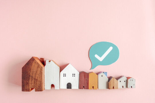 real estate, house, home, approved, mortgage, property, insurance wooden miniature models of buildings on pink background with a check mark icon representing home buying concept.