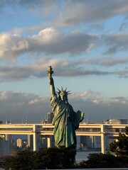 Statue stands tall, holding torch aloft against sky © Edra