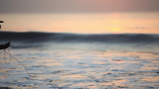 Silhouette of Fisherman Throwing Net into Ocean Waves at Sunset