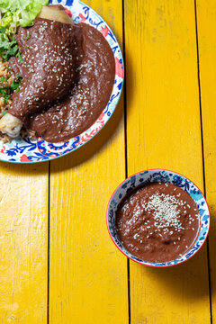 Delicious mole poblano served with tender chicken over a vibrant yellow table