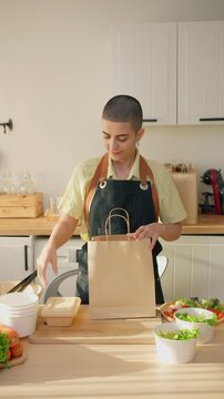 Caucasian woman preparing multiple salad bowls for small food business.