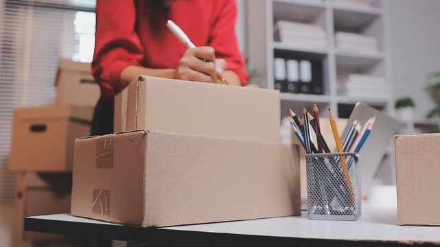 Close up with Start up small business, SME female owner using laptop checking order online to prepare to pack a box of goods for sale to customers, sme business idea.