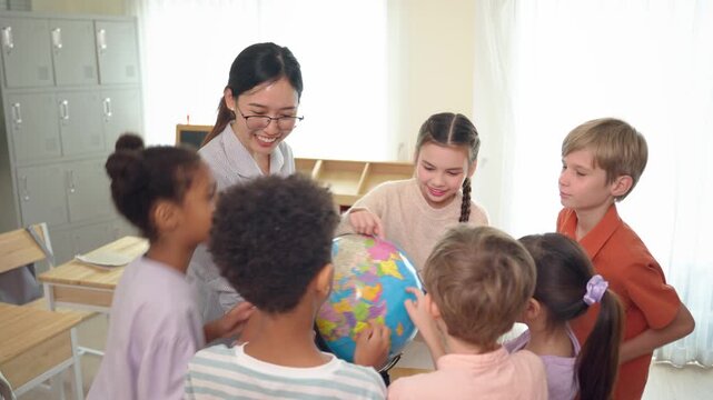 Asian female teacher using educational globe teaching students in classroom. 
