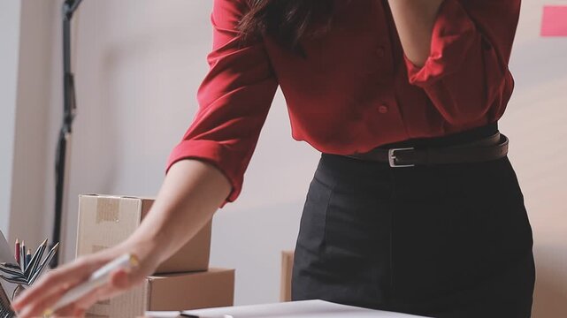 Close up with Start up small business, SME female owner using laptop checking order online to prepare to pack a box of goods for sale to customers, sme business idea.
