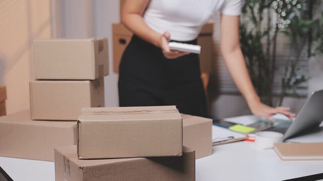 Close up with Start up small business, SME female owner using laptop checking order online to prepare to pack a box of goods for sale to customers, sme business idea.
