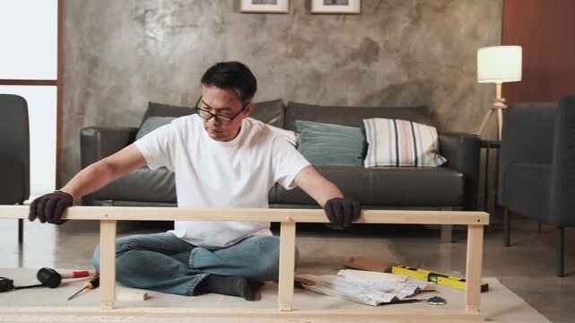 Asian mature man strength and precision checking, self-assembling flat-pack furniture with DIY tools, home improvement, expert craft installation, hobby wooden workshop, handyman active lifestyle.