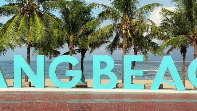 Close up panorama of Danang Beach Sign with Palm Trees in Background