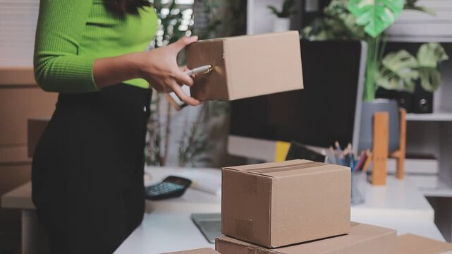 Close up with Start up small business, SME female owner using laptop checking order online to prepare to pack a box of goods for sale to customers, sme business idea.