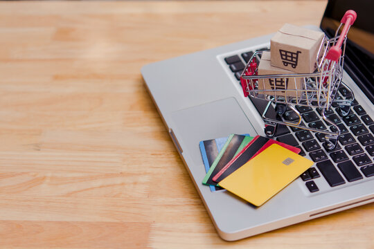 Online shopping cart on laptop with credit card payment and package box, e commerce concept