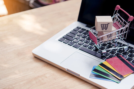 Shopping online. Credit card and cardboard box with a shopping cart logo in a trolley on laptop keyboard. Shopping service on The online web. offers home delivery