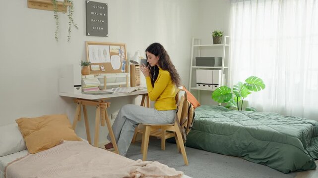 Young Latino female college student studying at desk in university dormitory. 